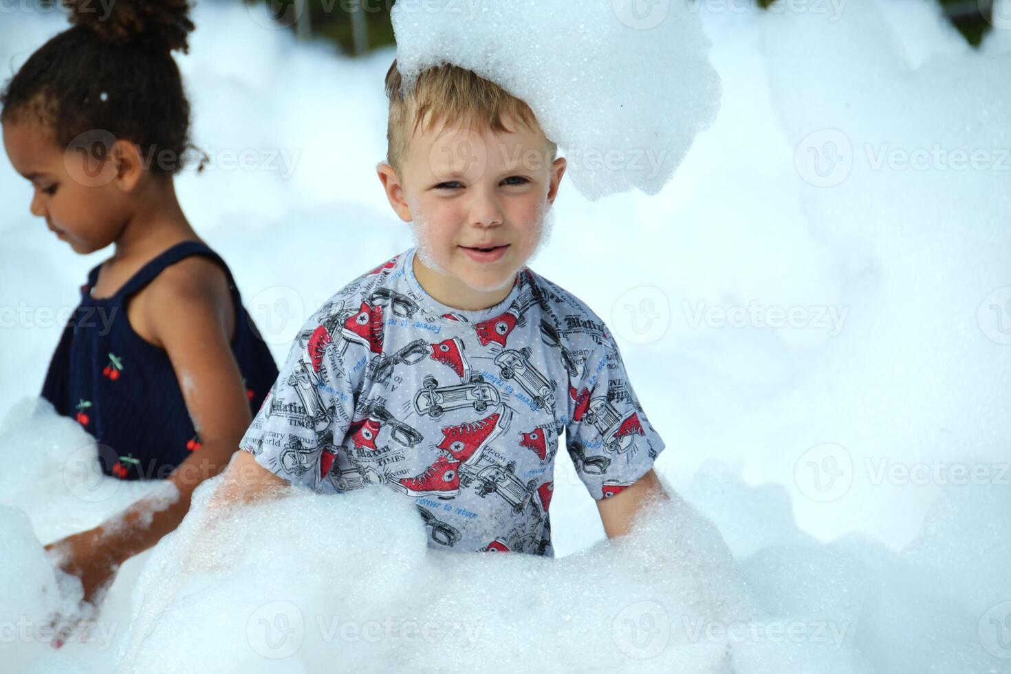 happy little boy with foam on his head, in wet clothes at a foam party photo