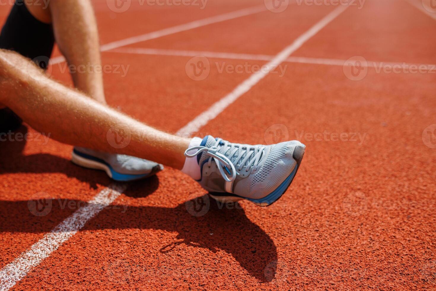An athlete sits on the track before running and prepares for the start of the competition photo