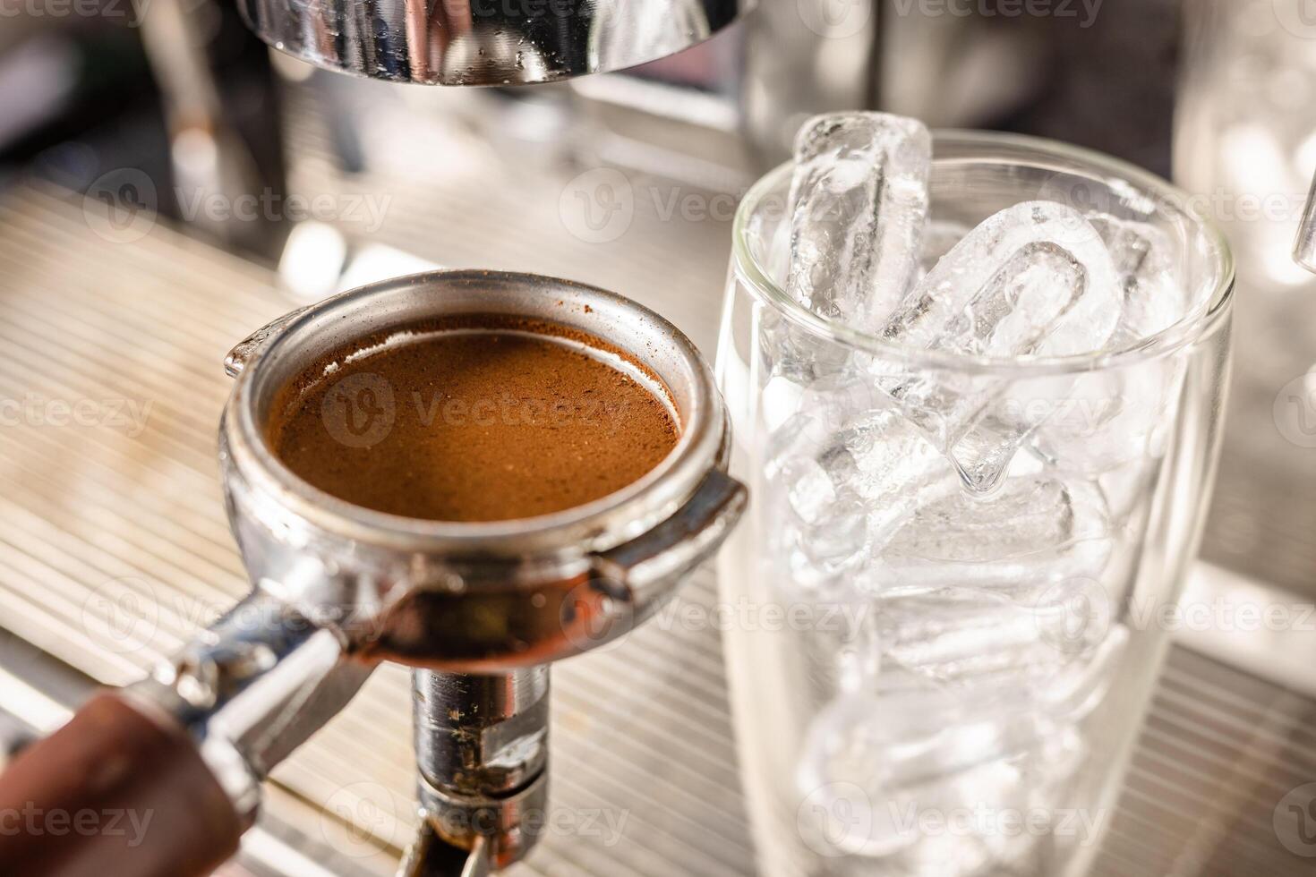 the barista's hand holds a cone with ground coffee near the coffee machine and prepares cold coffee photo