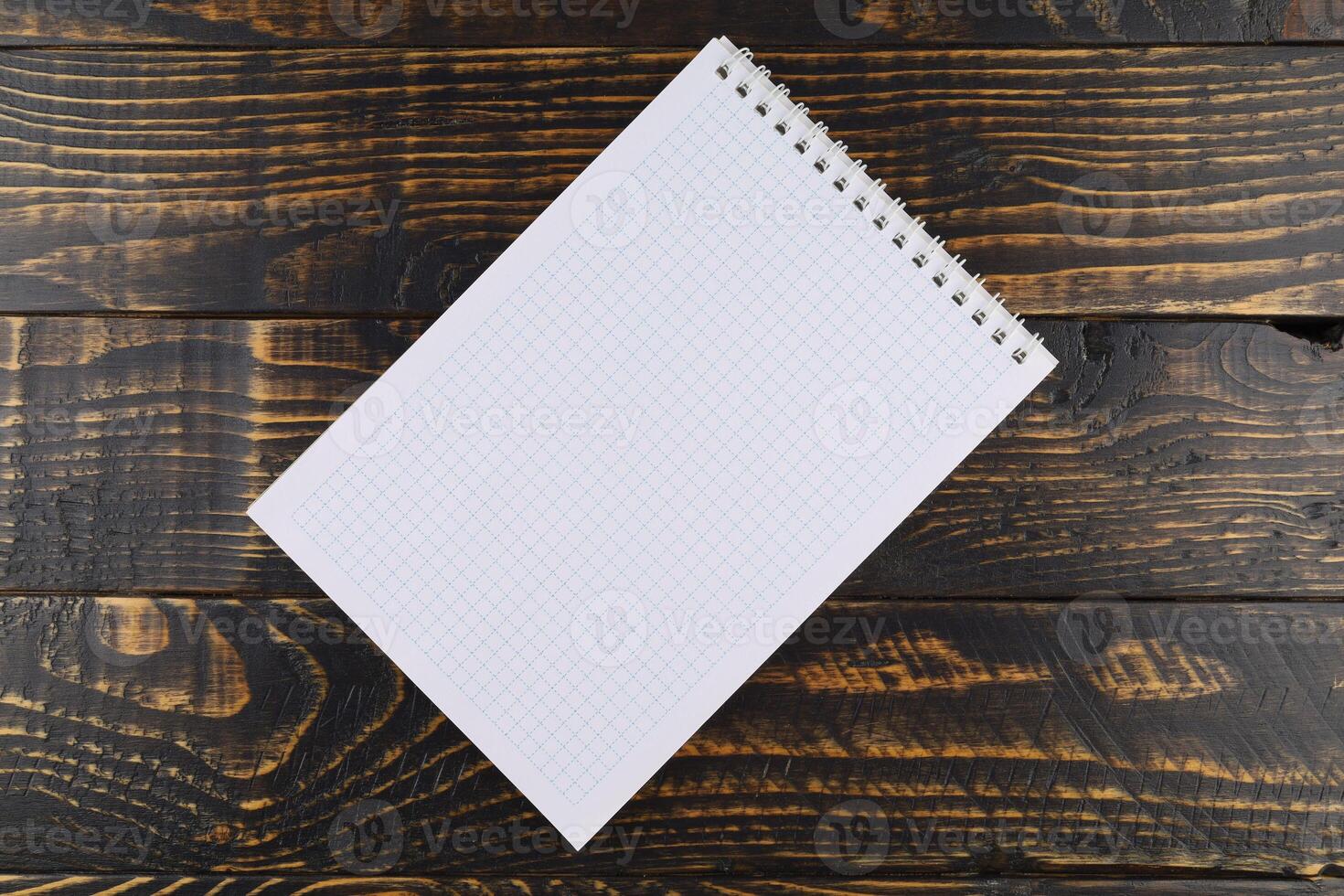 Notebook with cells on a wooden background. empty notebook on wooden table, top view photo