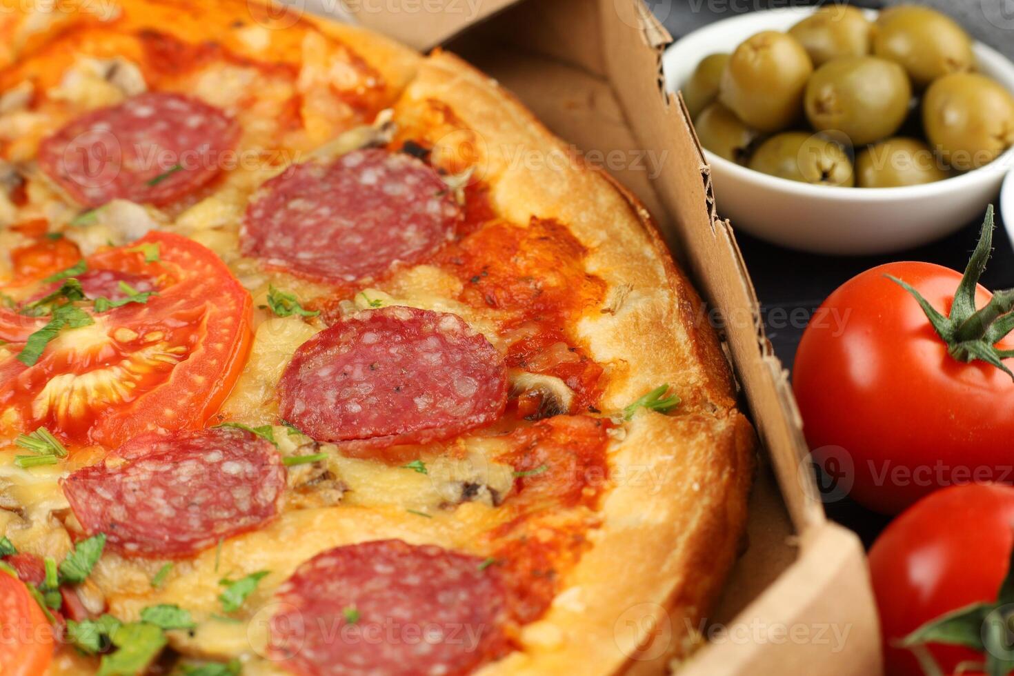 Pizza in a box on the table. Hot pizza with vegetables. Pizza in a restaurant. photo