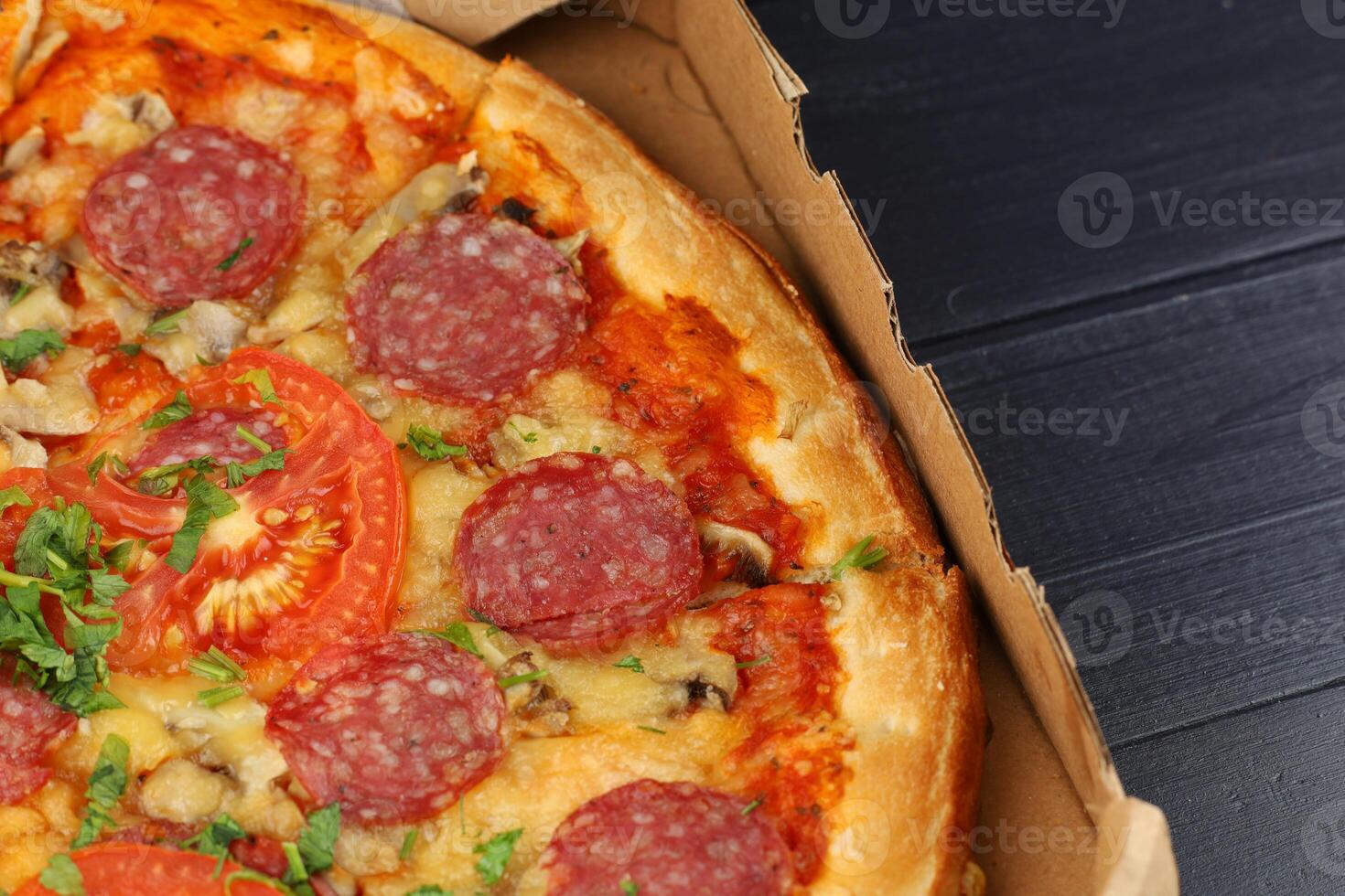 pizza in box open. Pizza in the in delivery box against a dark background photo