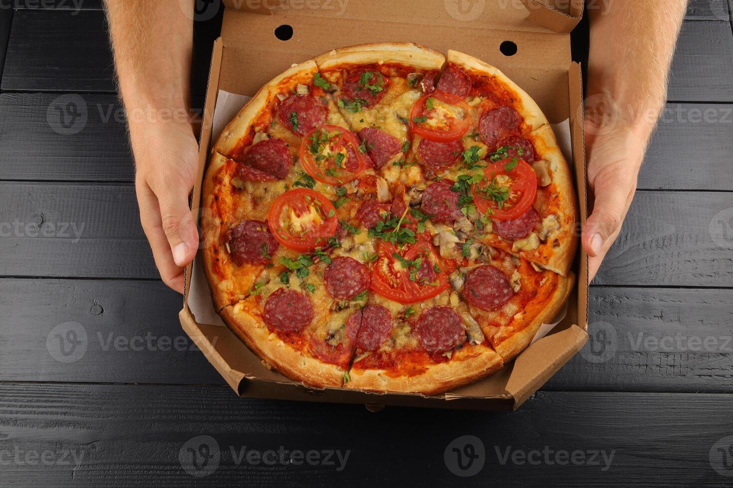 pizza in box open. Pizza in the in delivery box against a dark background photo