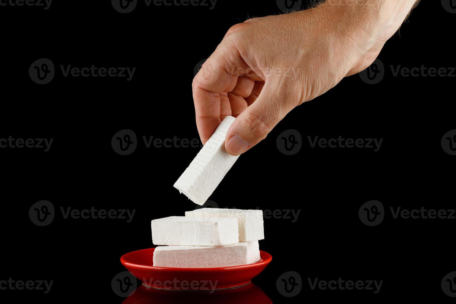 Lozenge in hand. A hand takes a white vanilla pastille sweet. photo