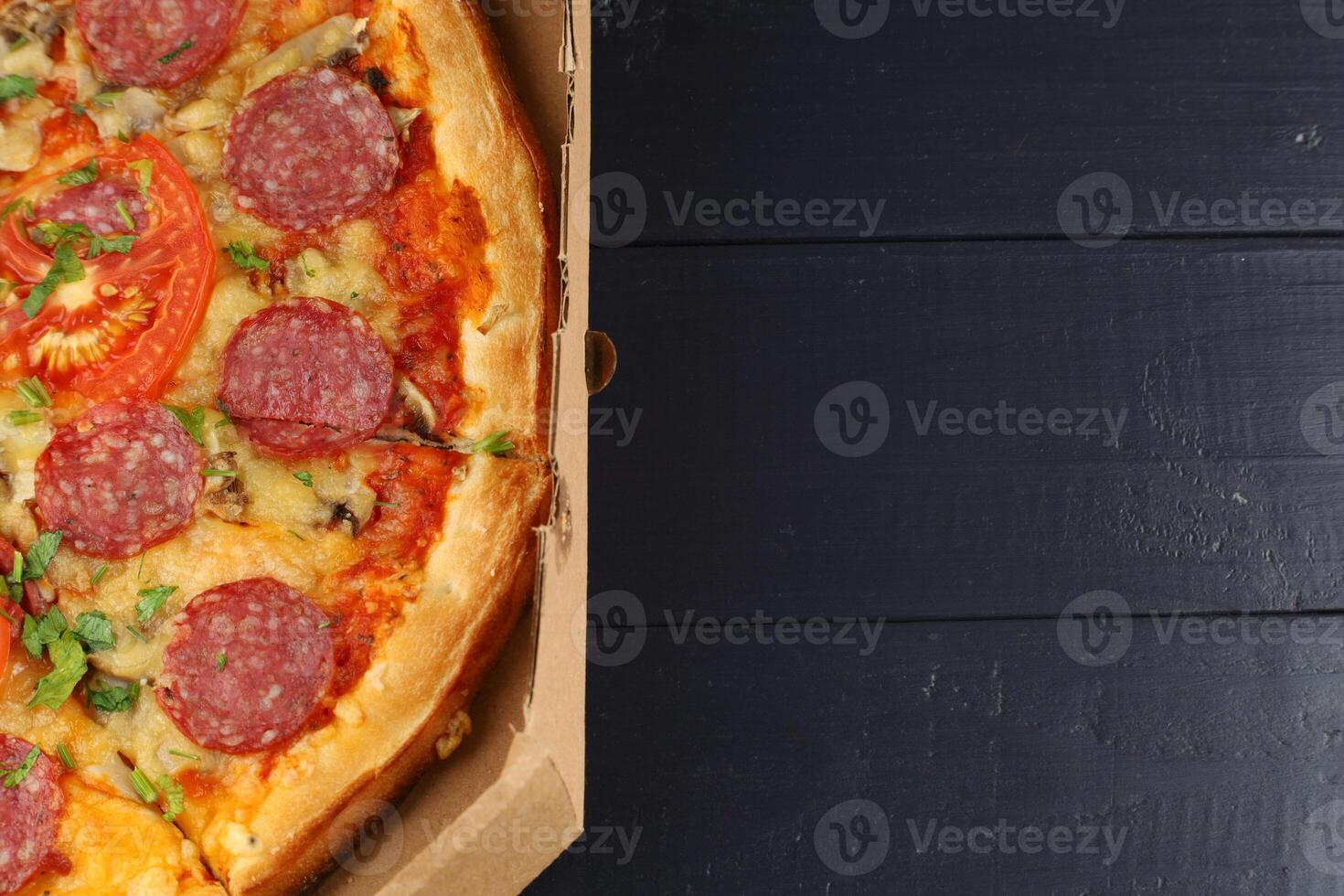 Pizza with salami and tomatoes in a box. place for text cope space photo