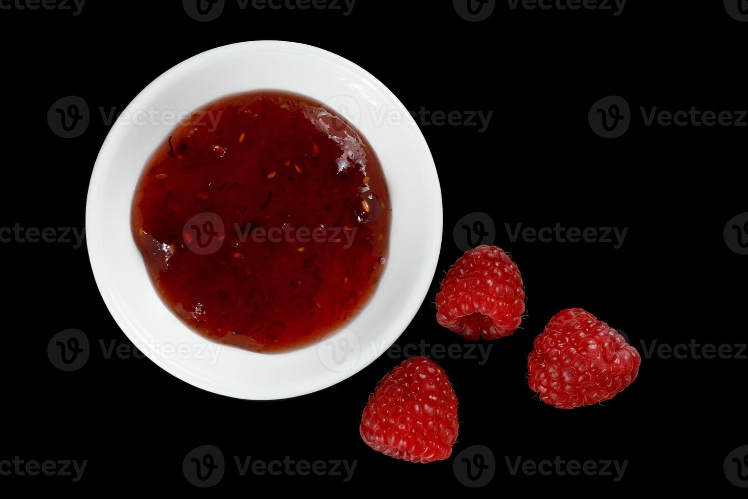 raspberries and jam on black. Jar with delicious raspberry jam photo