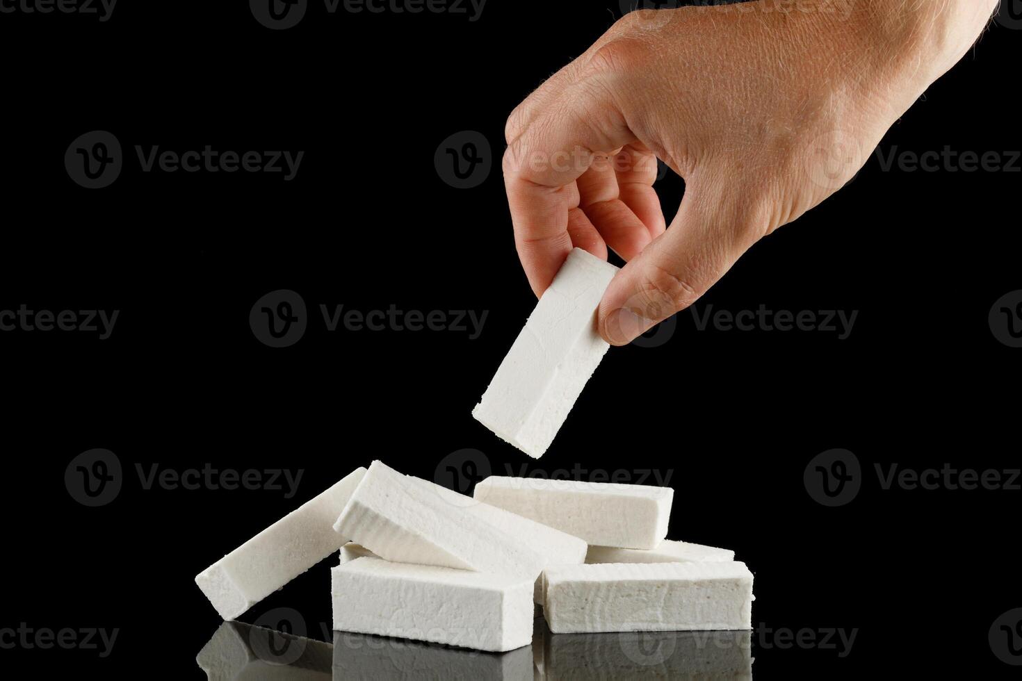 Lozenge in hand. A hand takes a white vanilla pastille sweet. photo
