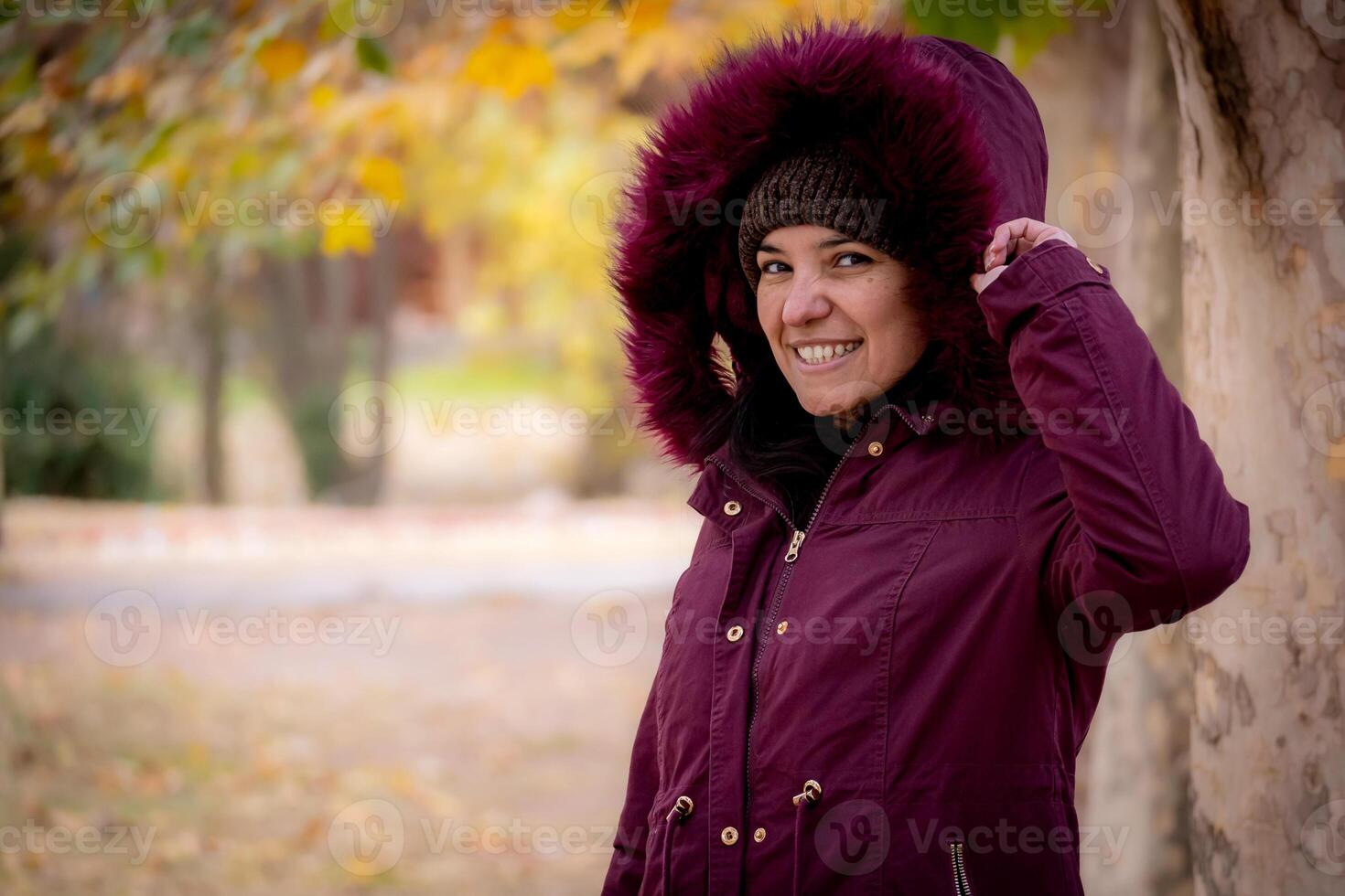 A middle aged woman dressed in a jacket and hood in autumn. She is smiling. photo