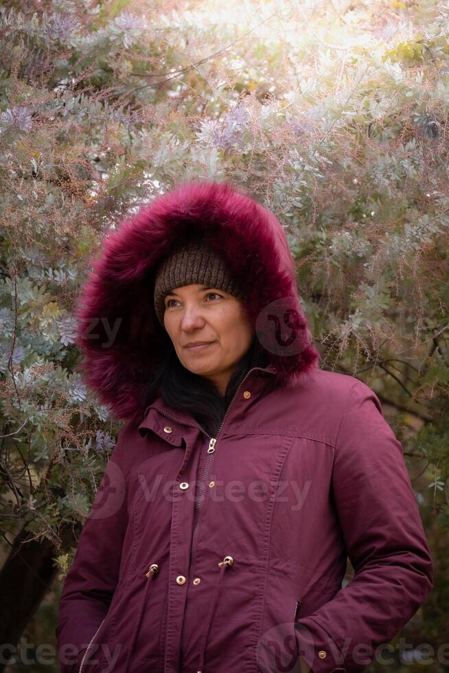 Middle aged Latin woman near some trees in autumn. photo