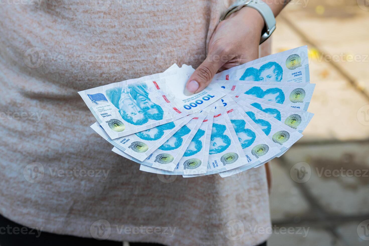10,000 Argentine peso bills in the hand of a woman. She has in her hands a total of 100,000 Argentine pesos. photo