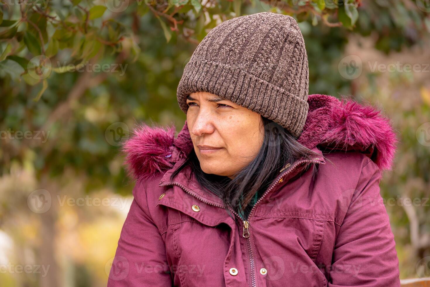 Latin woman sitting looking at the horizon with half-closed eyes in a park. photo