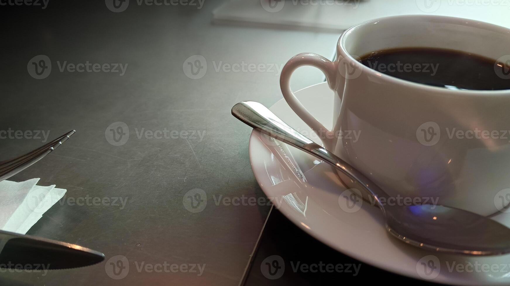 Black coffee in cup with spoon on table photo