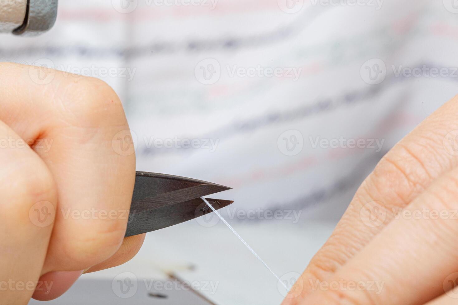 Female hands of a master tailor cuts a thread with scissors photo