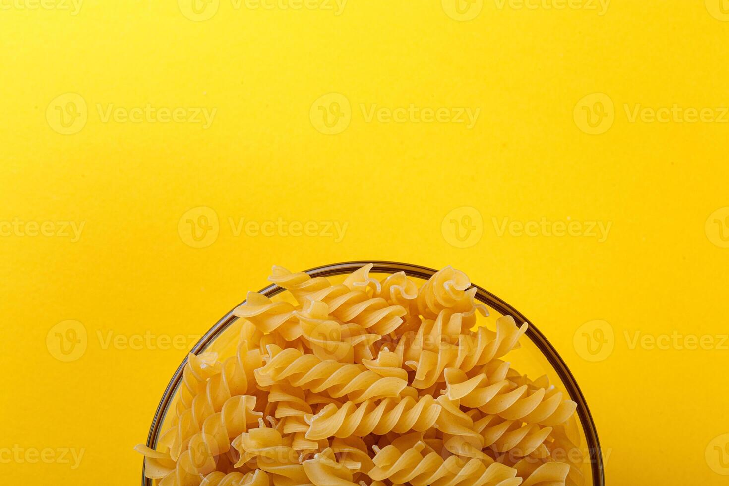 Different types and shapes of dry italian pasta on a yellow background photo