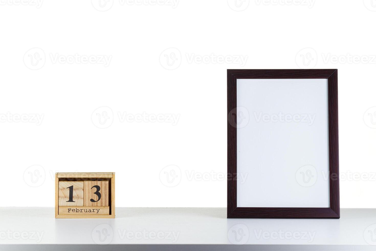 Wooden calendar 13 february with frame for photo on white table and background