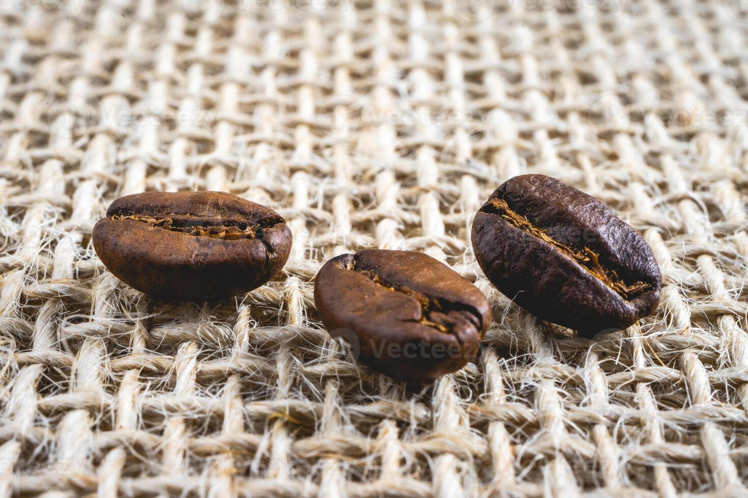 Close up from a few coffee beans laying down on a Burlap fabric background. Background voor coffee related products. photo
