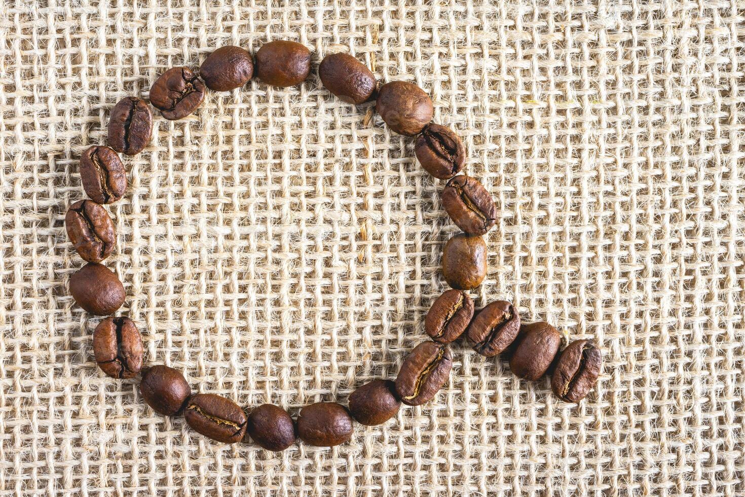 Coffee beans in the shape of a cup, on a burlap fabric. Background voor coffee related products. photo