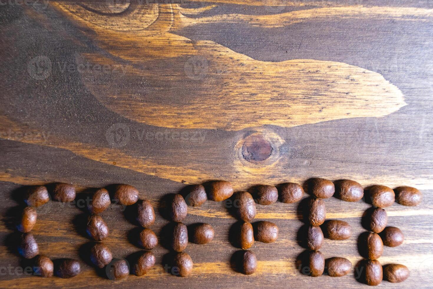 Coffee beans shaped in the letters coffee on a wooden background. Decorative banner for coffee products. photo