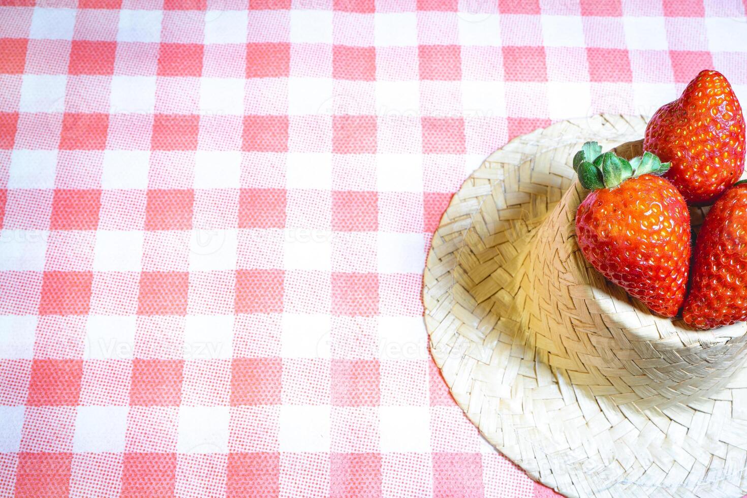 Fresh strawberries decorated on a straw hat. on a red picnic blanket. photo