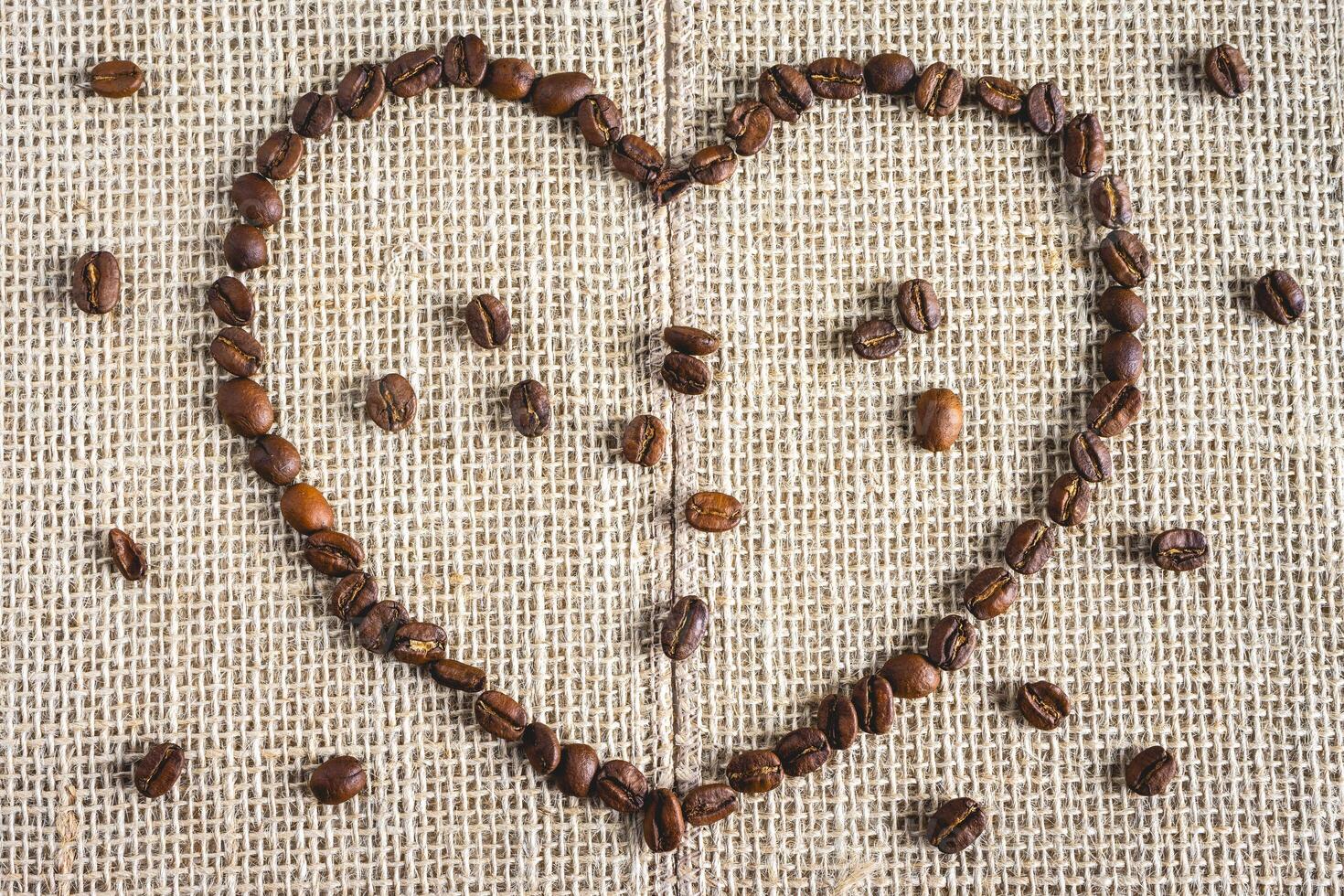 Coffee beans laying down in a heart shape, On a Burlap fabric. Background voor coffee related products. photo