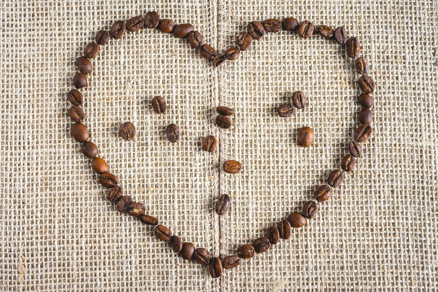 Coffee beans laying down in a heart shape, On a Burlap fabric. Background voor coffee related products. photo