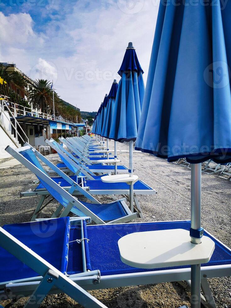 deckchairs and umbrellas lined up on a beach on the Ligurian coast in the summer of August photo