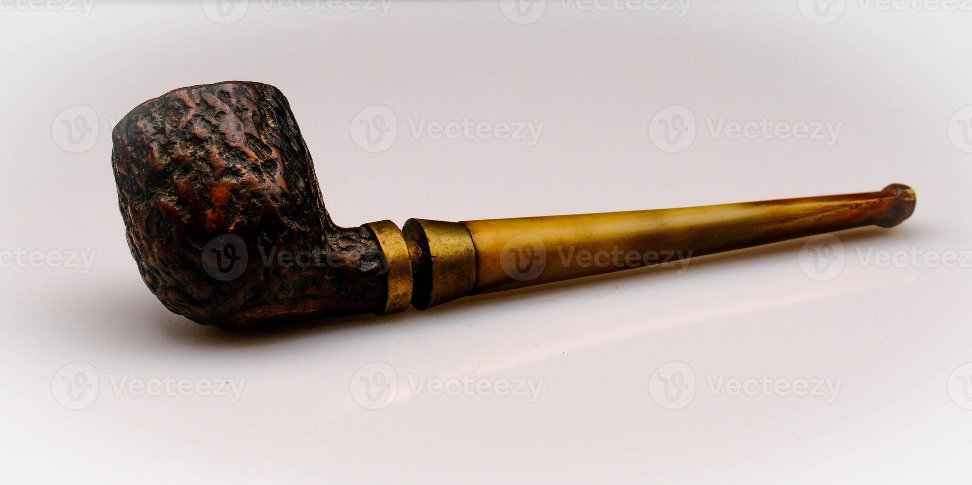 the pipe is an inlaid wooden object and is used for smoking tobacco. Here it is photographed against an isolated white background photo