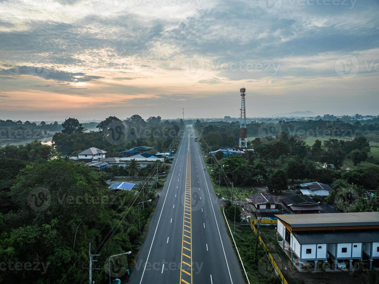 A long straight road leading through rural countryside with beautiful forest. photo