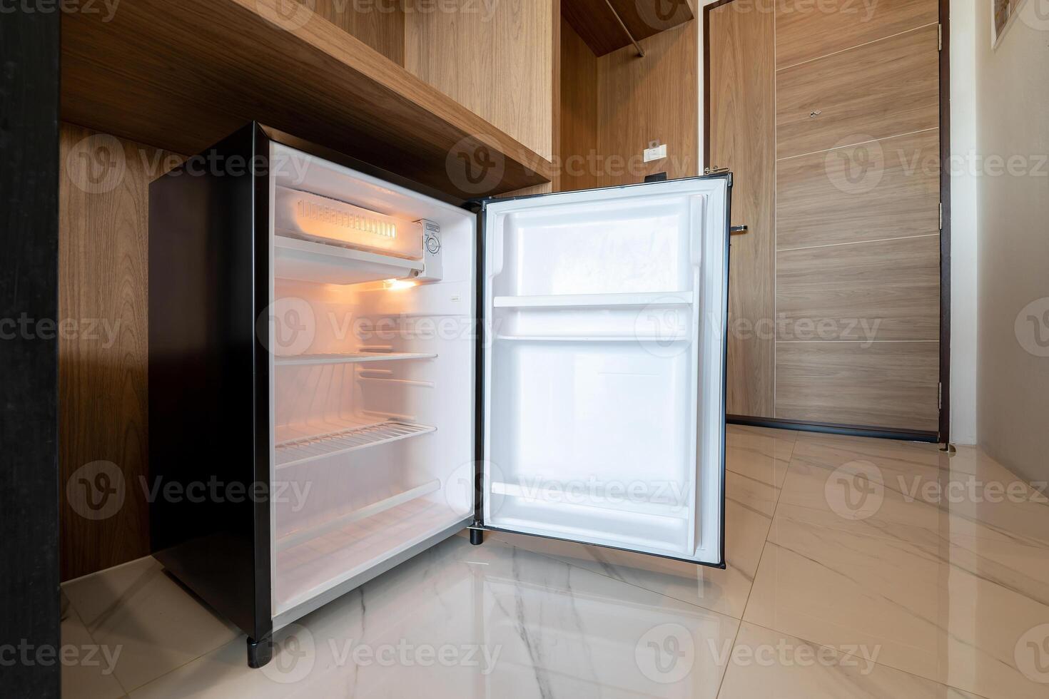 Opened small refrigerator under the wood counter and in front of enter door delux room at resort and hotel. photo