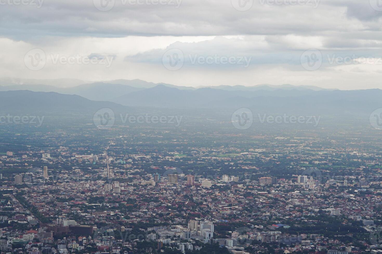 Top view of mountain in Chiang Mai City, Thailand. White cloud and dust is above of the mountain while cities can be seen far away. photo