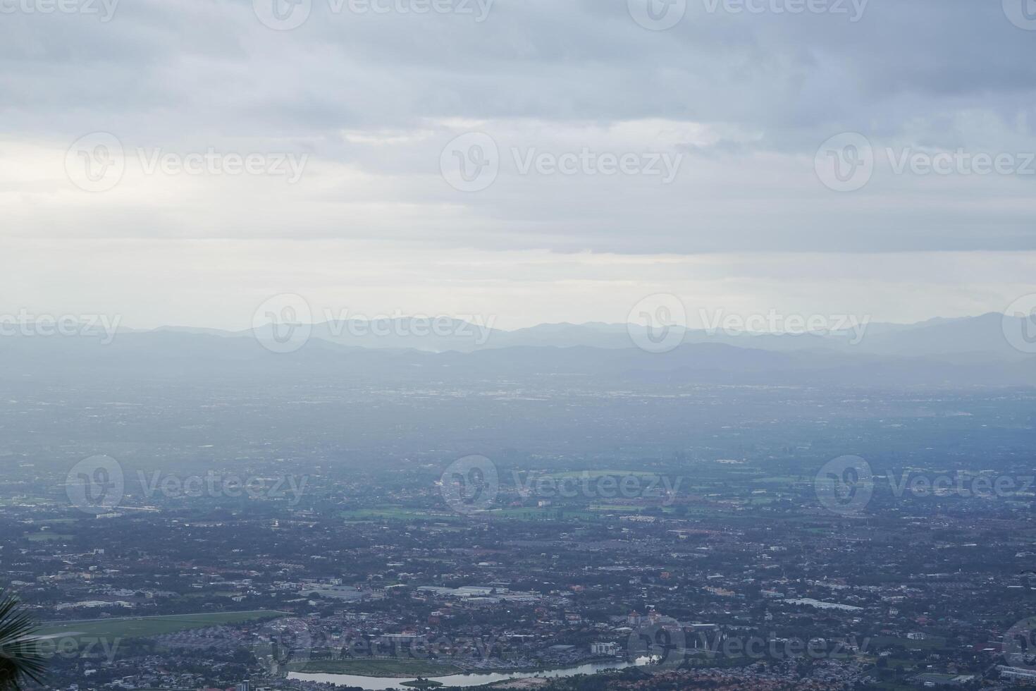 Top view of mountain in Chiang Mai City, Thailand. White cloud and dust is above of the mountain while cities can be seen far away. photo
