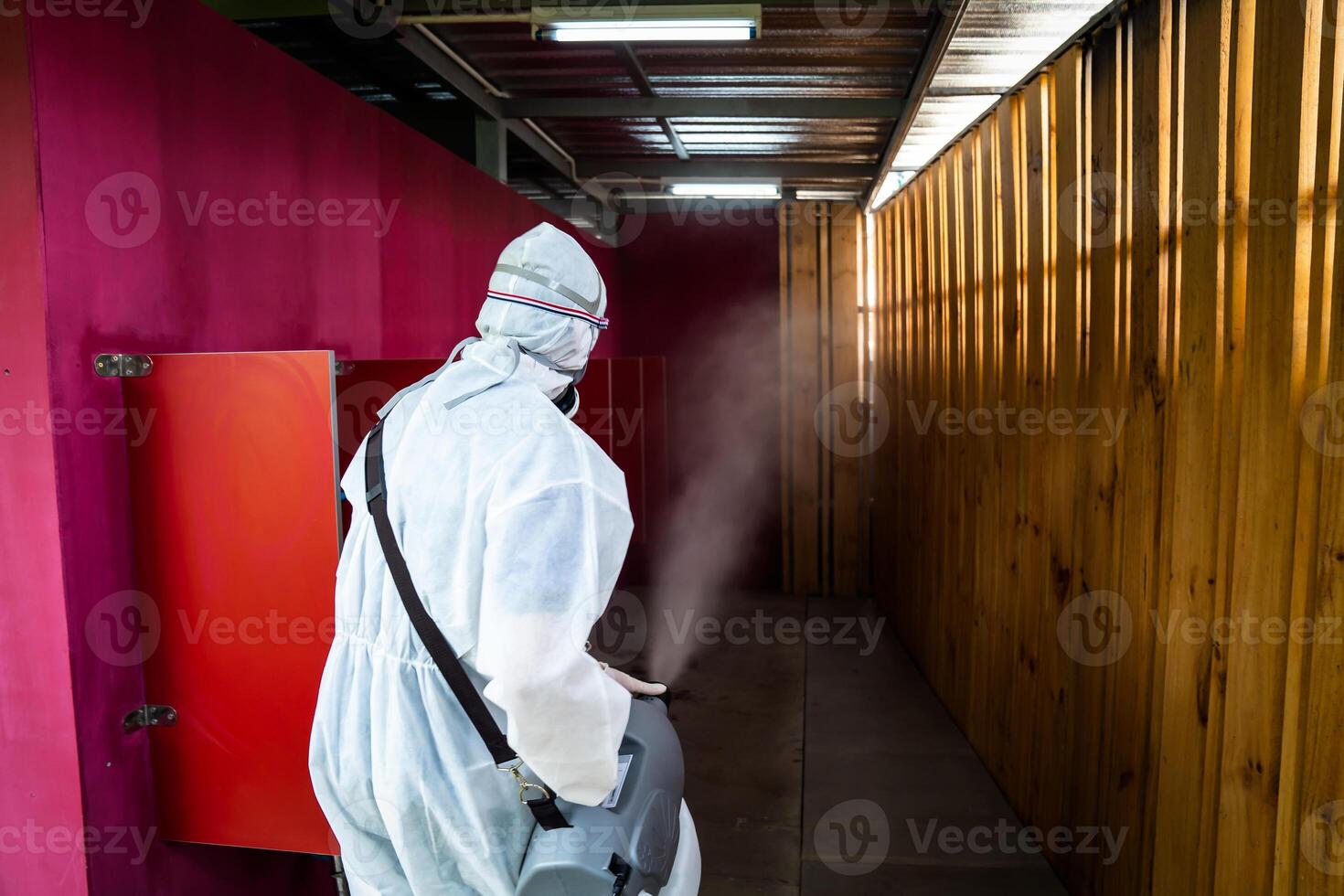 Professional technical man in prevention suit with his sterilizing machine and disinfecting water sprays in toilet or wc area field for purifying coronavirus COVID-19 photo