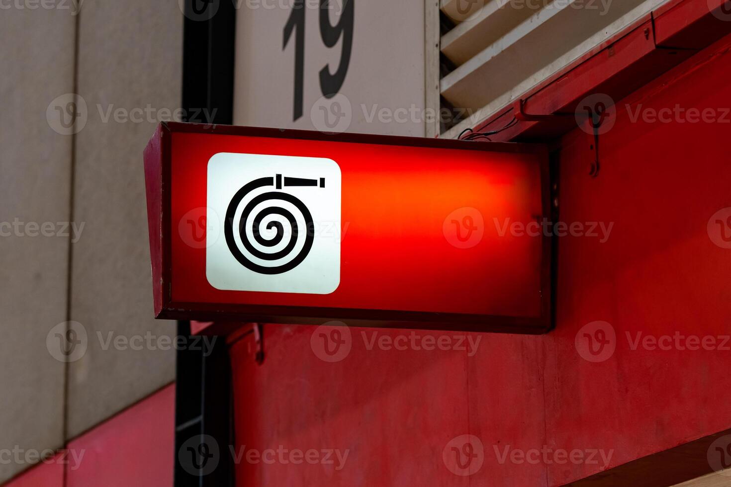 A fire equipment sign installed on a wall. Red light on to be noticeable in an exhibition hall that contains many participants. photo
