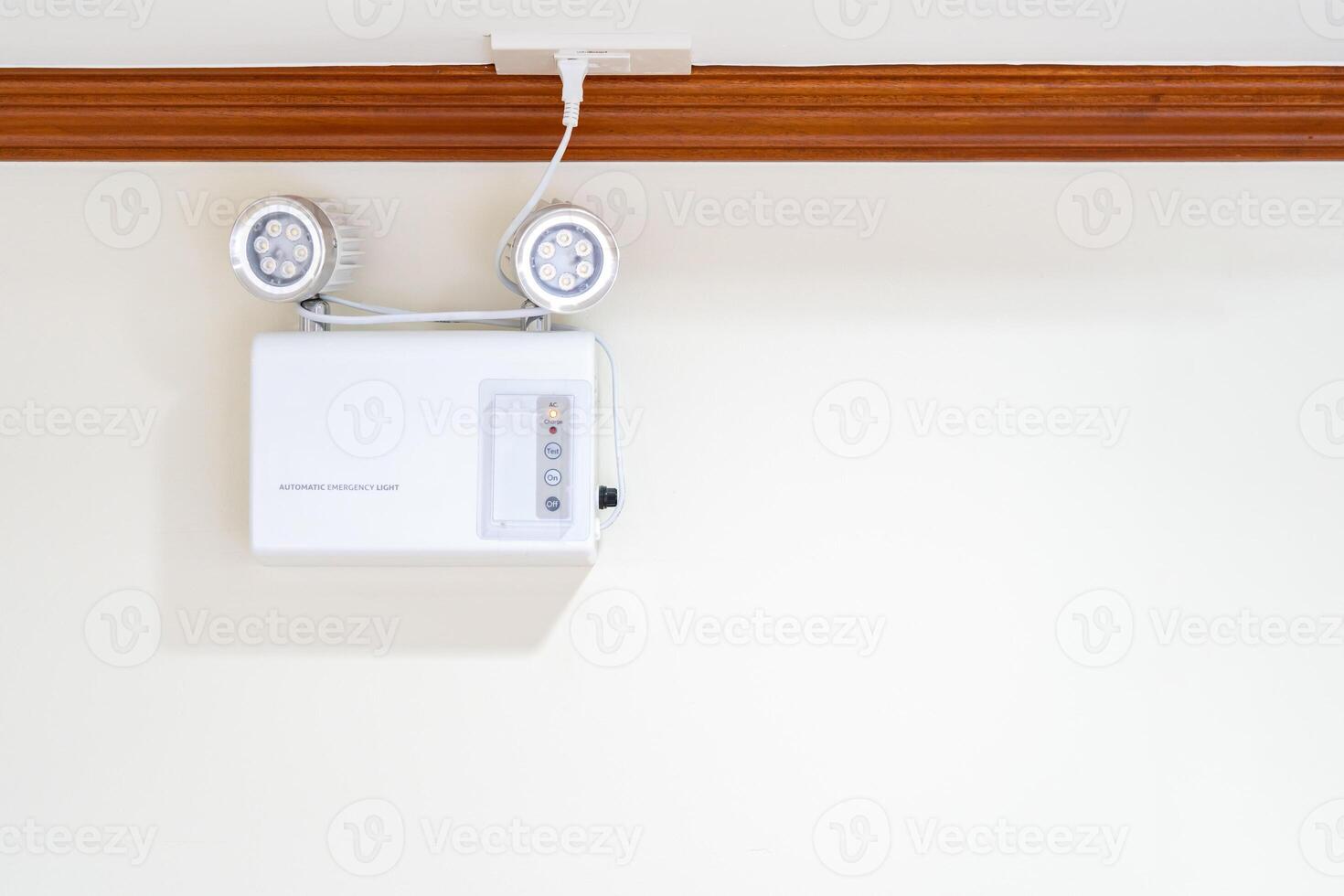 Automatic EMERGENCY LIGHT in hospital is charging and power pluging on the wall that ready to use when the power went out. photo