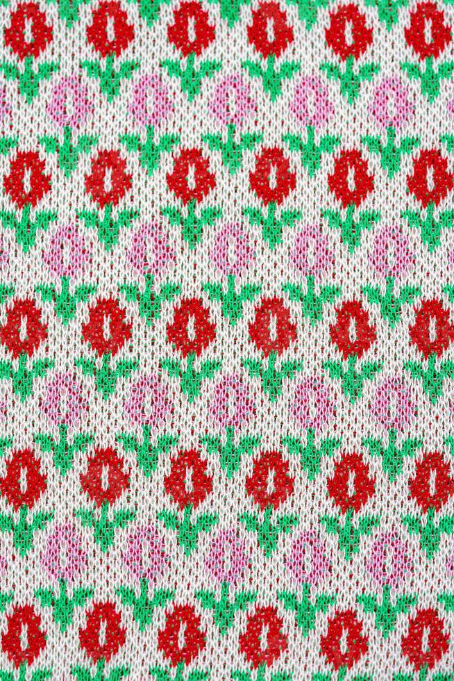 This cardigan fabric have a texture of geometric pattern with colourful red pink and green tulip flowers. photo