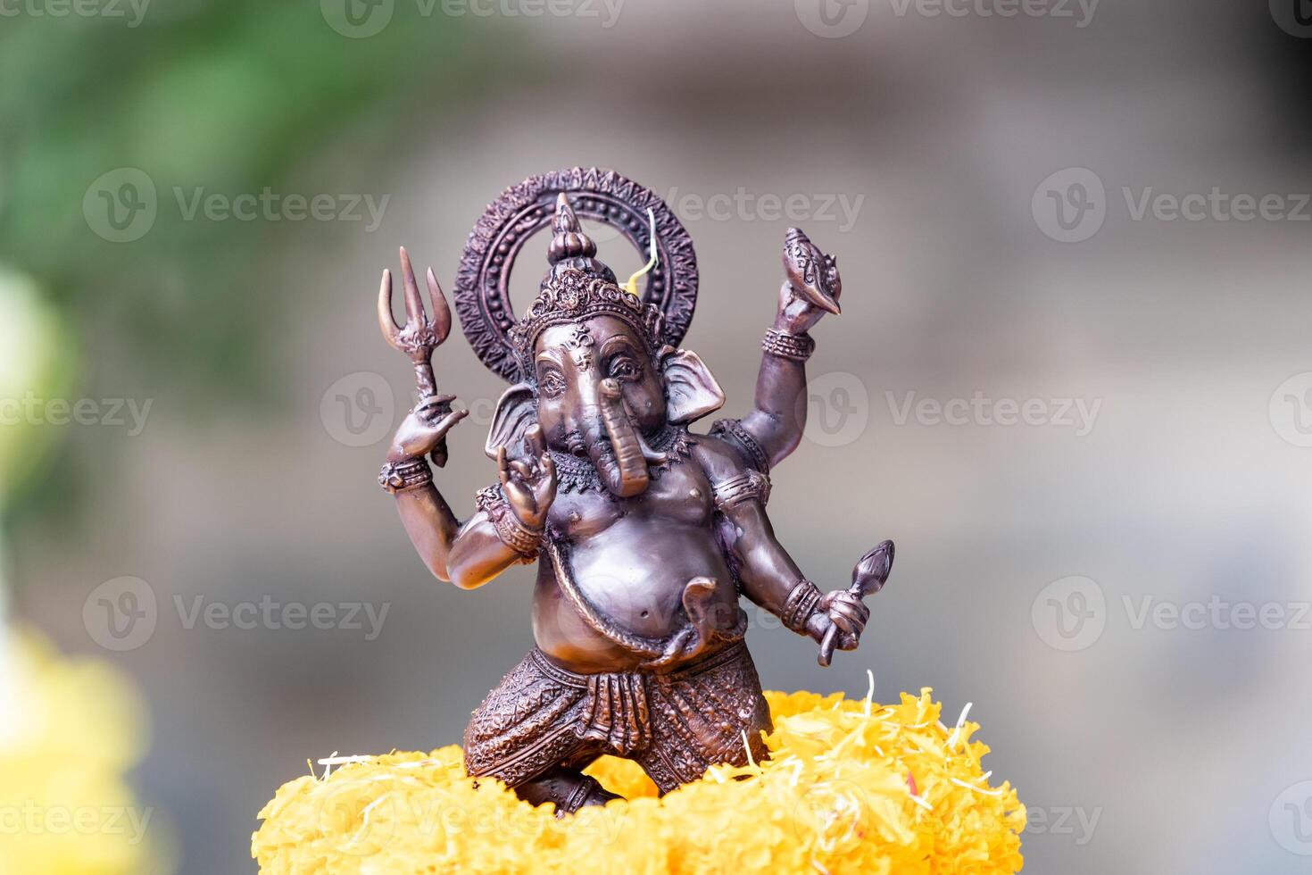 Small replica of Ganesh with iron color is worshiped with a glowing yellow marigold. photo