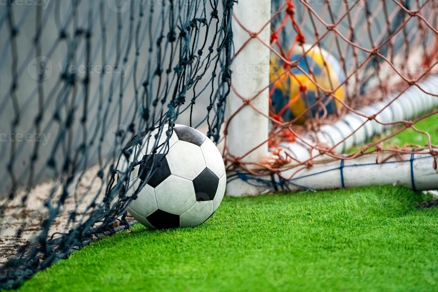 Classical football or soccer ball and goal lying on the artifinal grass. They are ready to play by football player indoor arena. photo