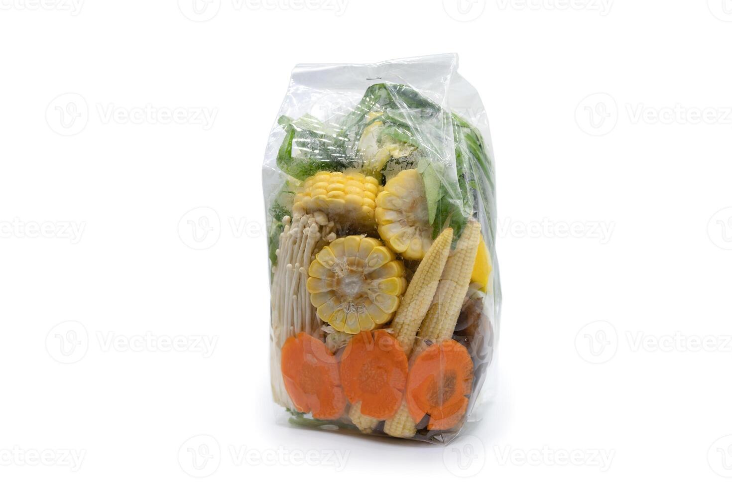 Carrots, vegetables, corn, and golden needle mushrooms are ready for sale in transparence plastic bags on white background. Clipping Path. photo