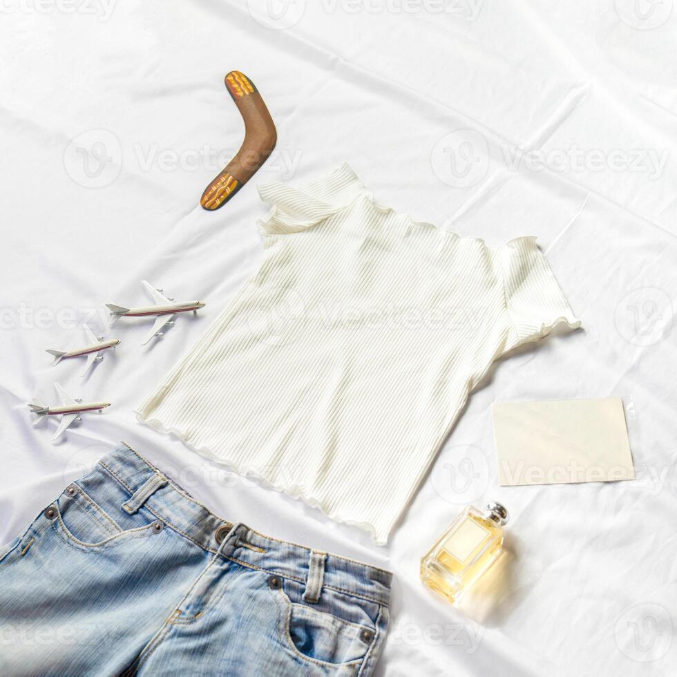 On the table were models card, perfumes and notebooks lying around a white shirt and jeans. photo