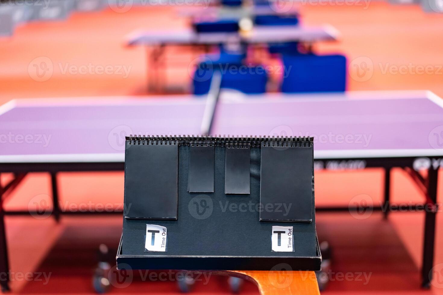 A tennis table black scoreboard is placed next to the table tennis table for referee count the score, which acts as a blurred background of pingpong tournament. photo