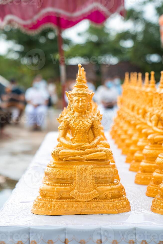Golden Buddha statues placed on the white table, which were wet by rain felled and prepared for a religion ceremony event. photo