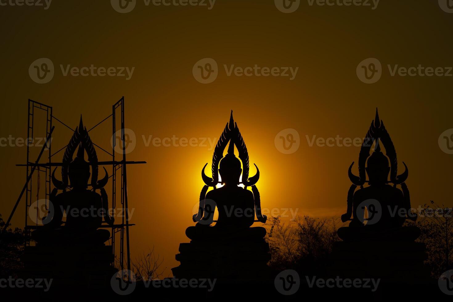 Silhouette Buddha statue between creating and building process, at outdoor field with the sun set and twilight period time., Thailand. photo