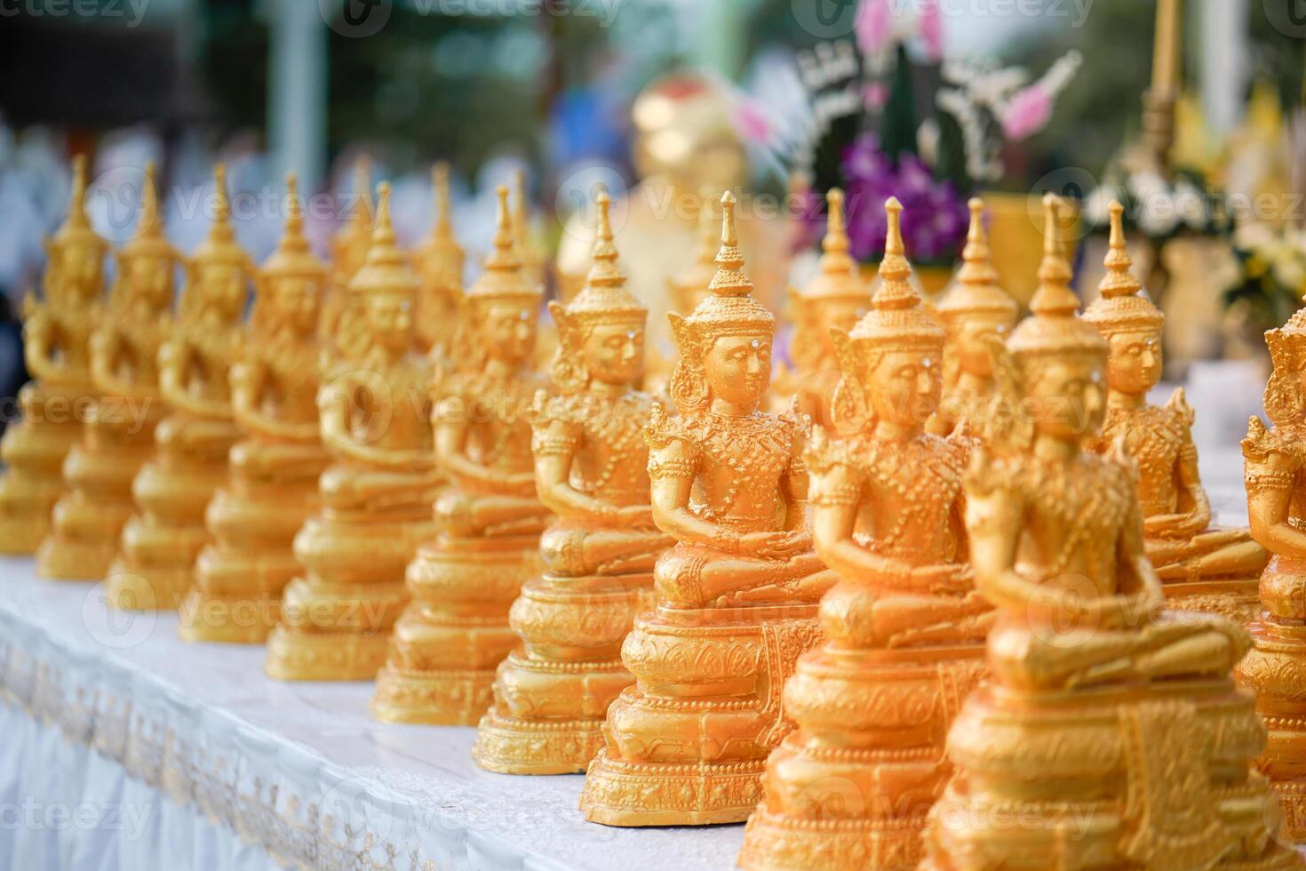 Golden Buddha statues placed on the white table, which were wet by rain felled and prepared for a religion ceremony event. photo
