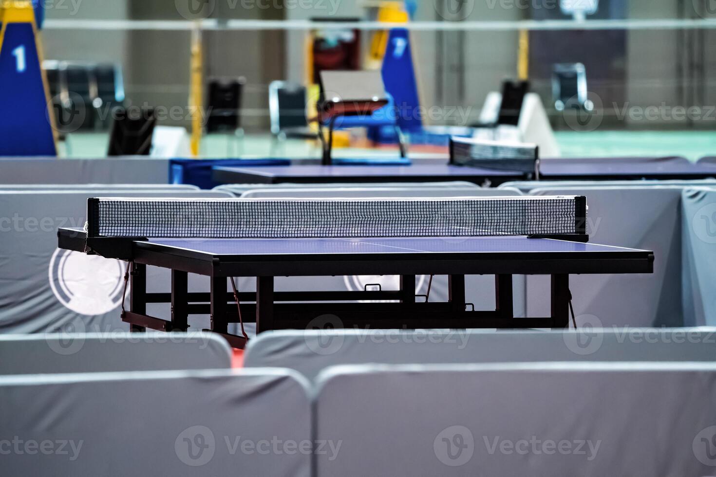 Blue table tennis or pingpong table is settle on a red, orange floor of the indoor court stadium for competitions tournament. photo