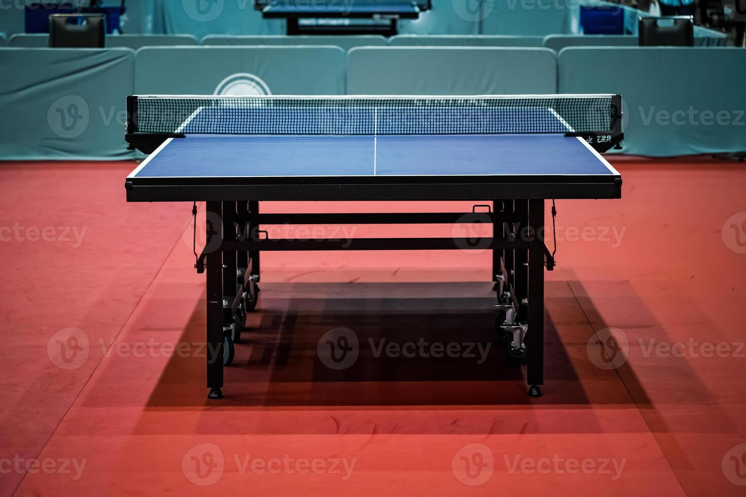 Blue table tennis or pingpong table is settle on a red, orange floor of the indoor court stadium for competitions tournament. photo