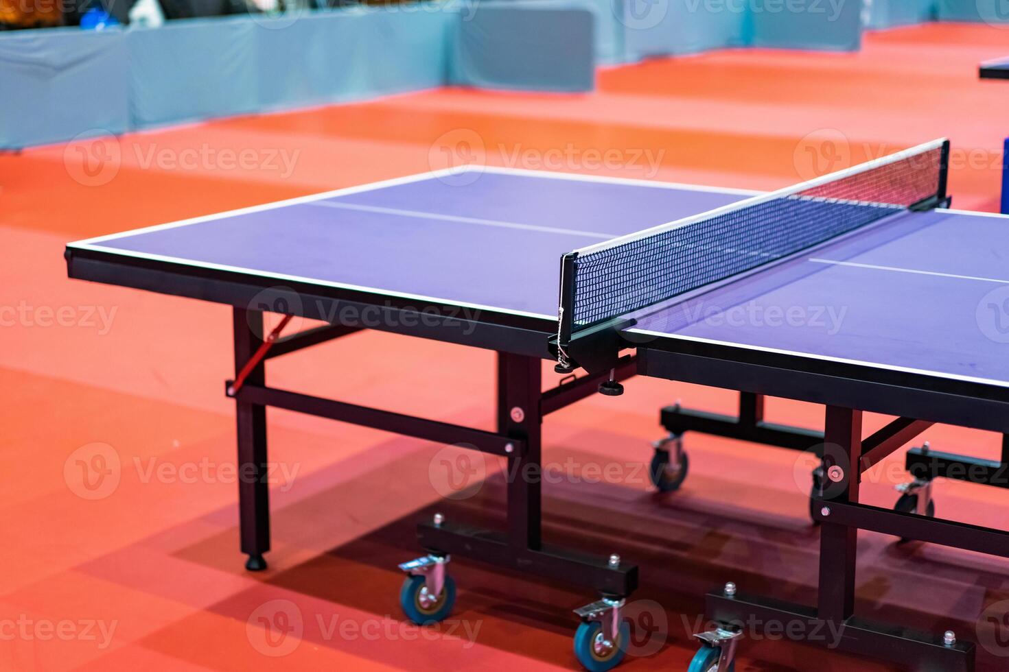 Blue table tennis or pingpong table is settle on a red, orange floor of the indoor court stadium for competitions tournament. photo