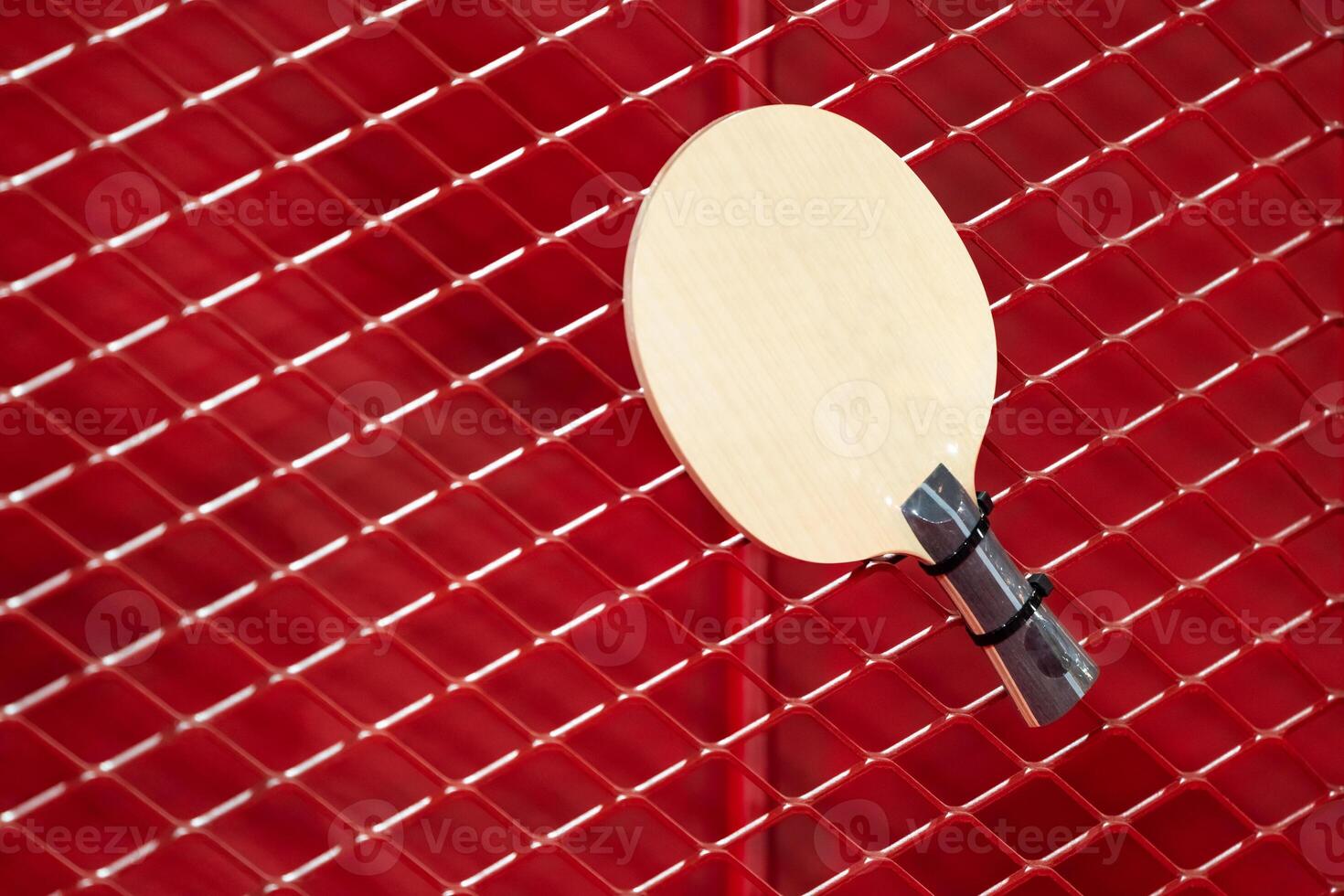 one Table Tennis Paddle racket is hung on red grill by a cable tie for display in exhibition sports event photo