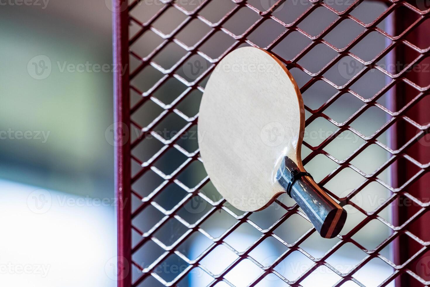 one Table Tennis Paddle racket is hung on red grill by a cable tie for display in exhibition sports event photo