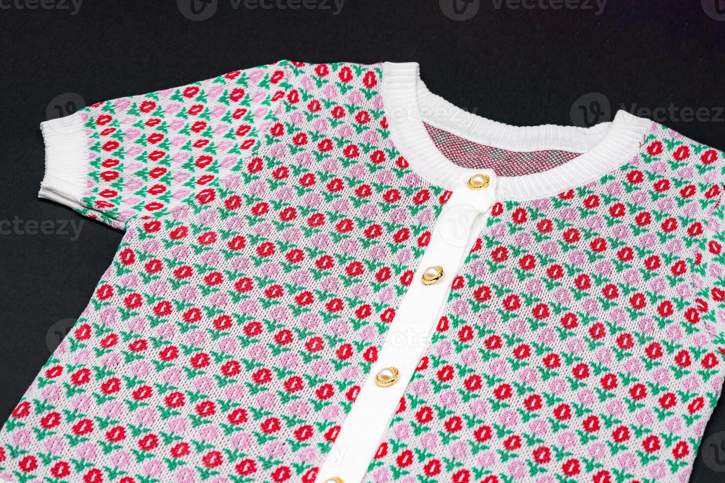 flat White knitwear pink red flower pattern sweater tshirt shape with pearl and gold circle buttons on black background with studio light photo