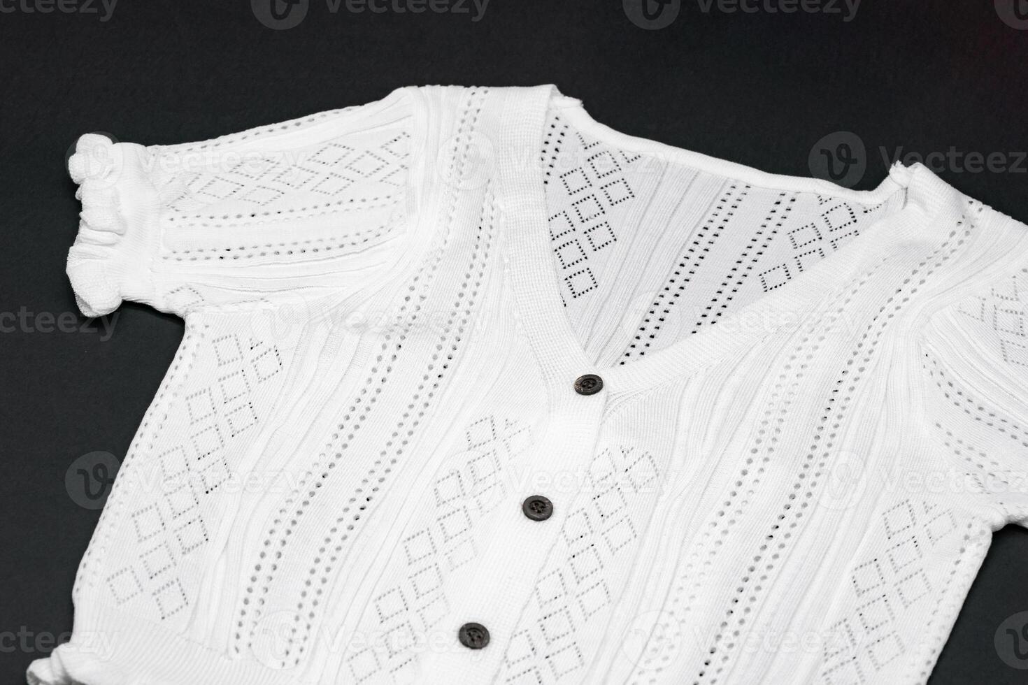 close up to flat White knitwear tshirt shape on black background with studio light. photo